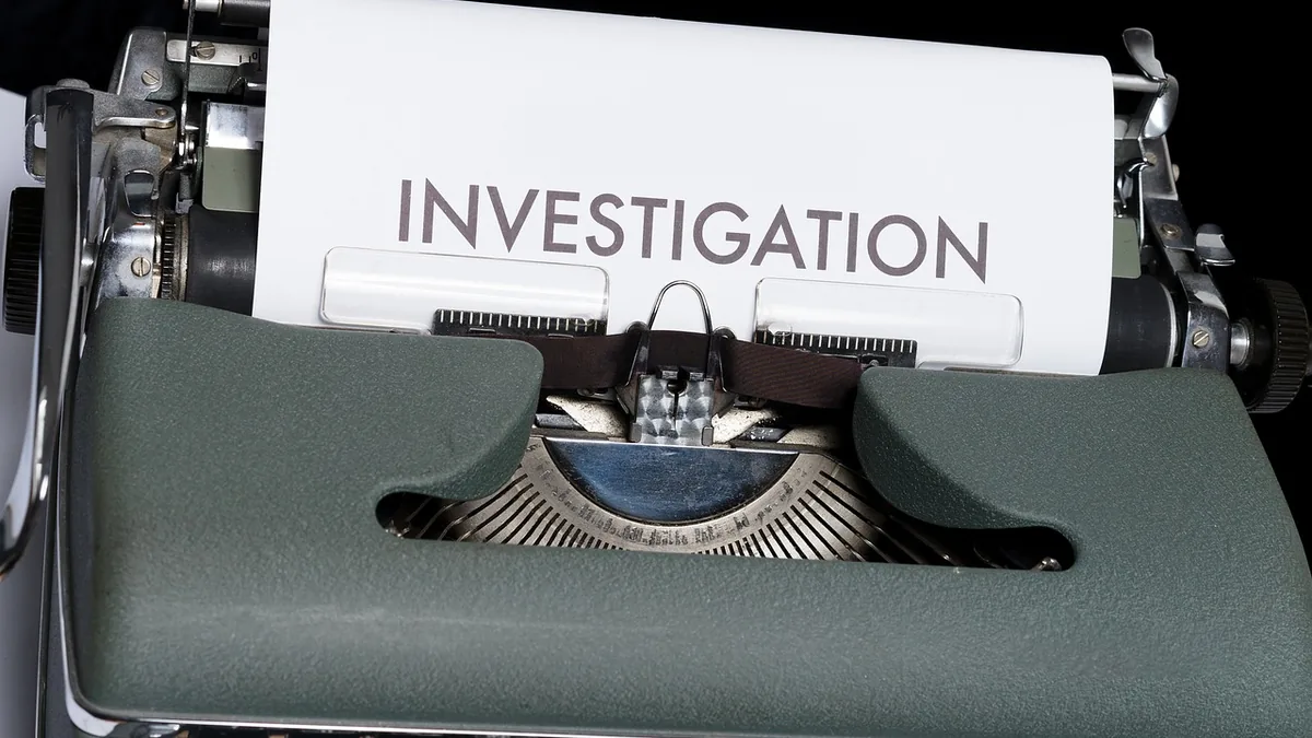 A vintage typewriter with a sheet of paper displaying the word 'INVESTIGATION' in bold letters.