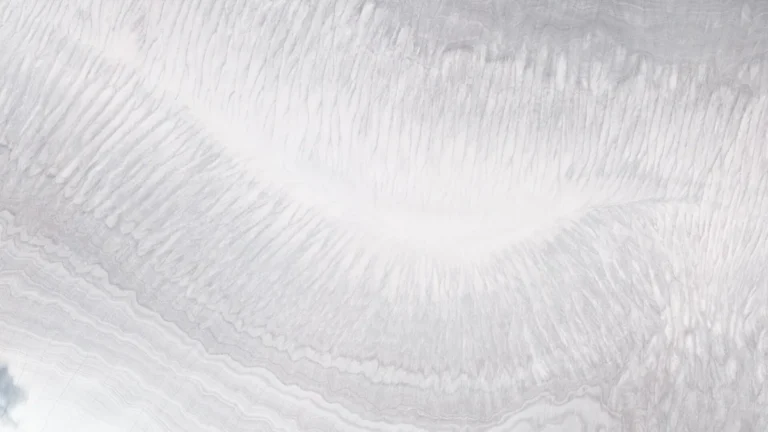 Detailed close-up of white ice cap layers showing intricate flow lines and subtle grey bandings.