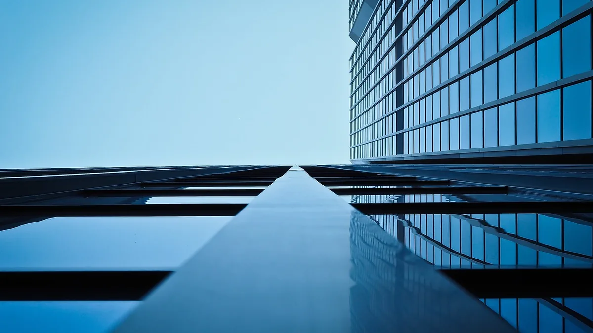 Low-angle view of towering blue glass skyscrapers reflecting the sky and each other in sharp perspective.