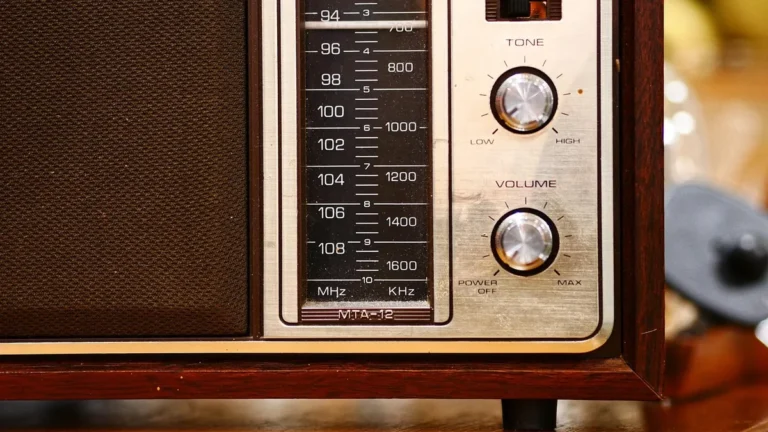 Close-up of a vintage wooden radio dial showing frequency scales, tone, and volume knobs.