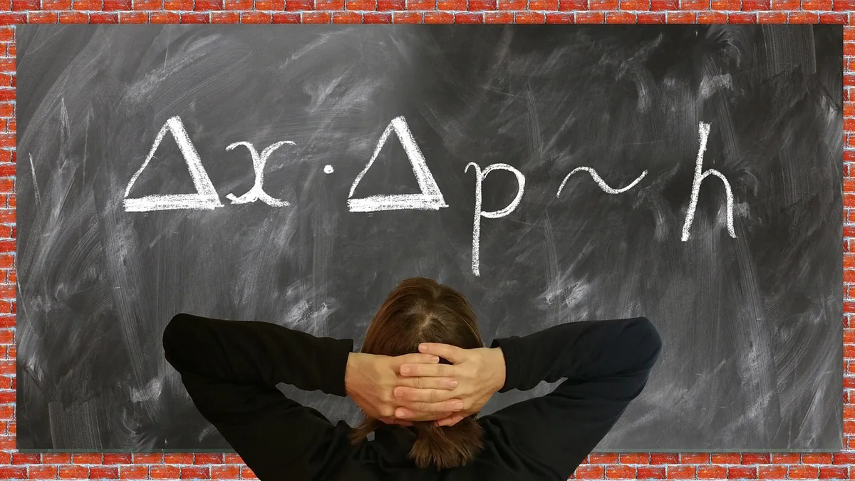A person from behind looks at a blackboard with the Heisenberg uncertainty principle formula written in chalk.