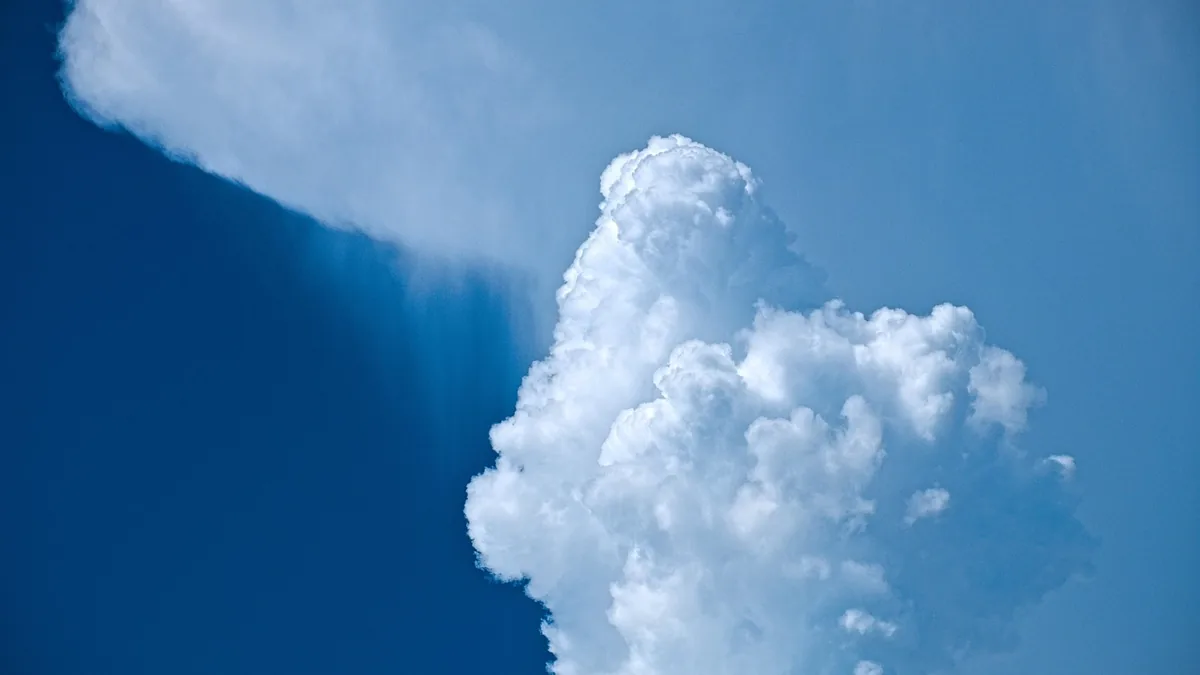 A massive white cloud towers against a vibrant blue sky, visually representing cloud-based infrastructure.