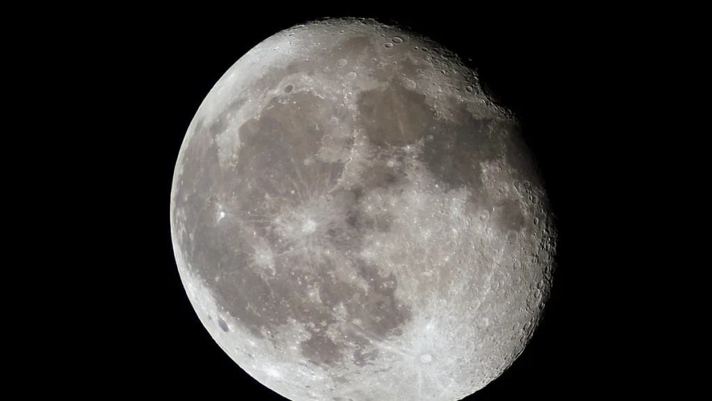 Detailed view of the Moon's cratered surface and lunar maria against a deep black space background.