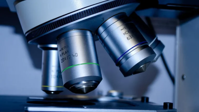 Close-up of silver microscope objective lenses on a laboratory stand.