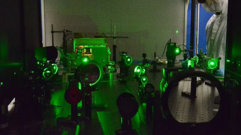 Green laser light illuminates optical equipment on a lab table, showcasing advanced photonics technology.