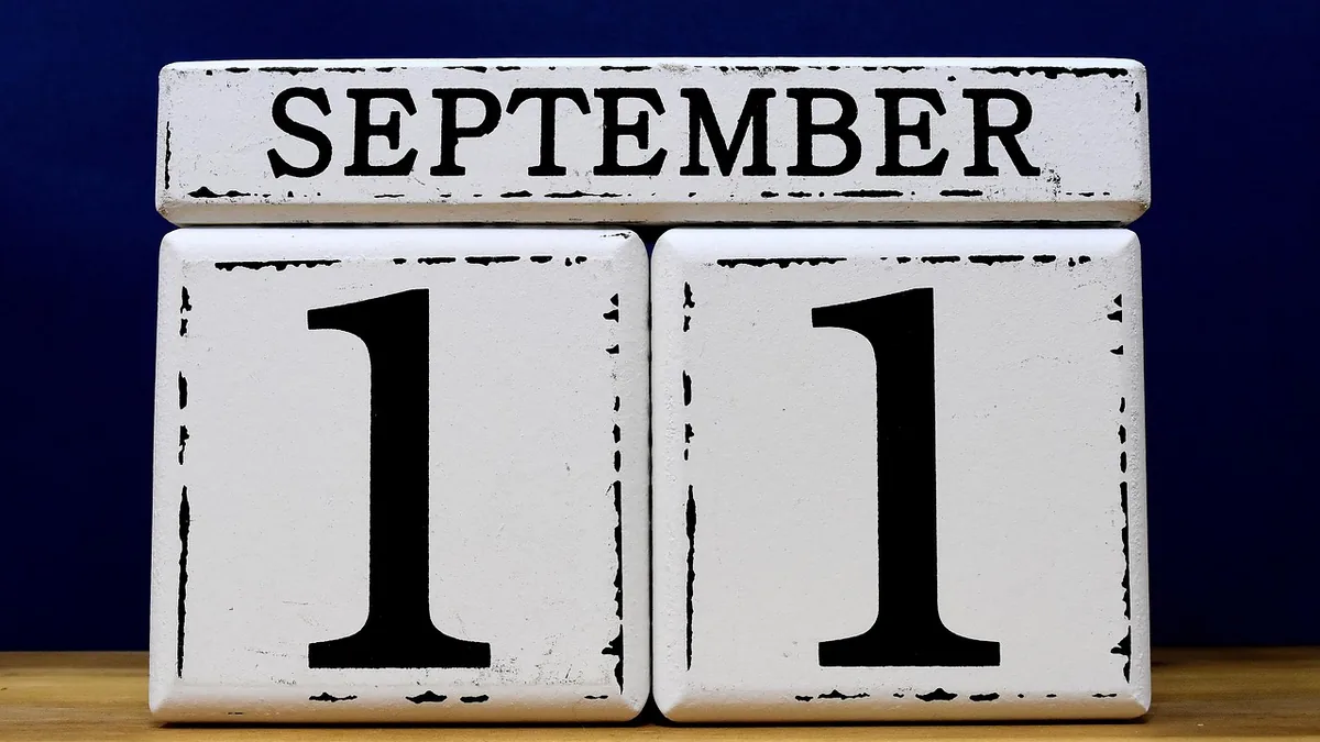 White wooden block calendar displaying the date September 11 against a dark blue background.