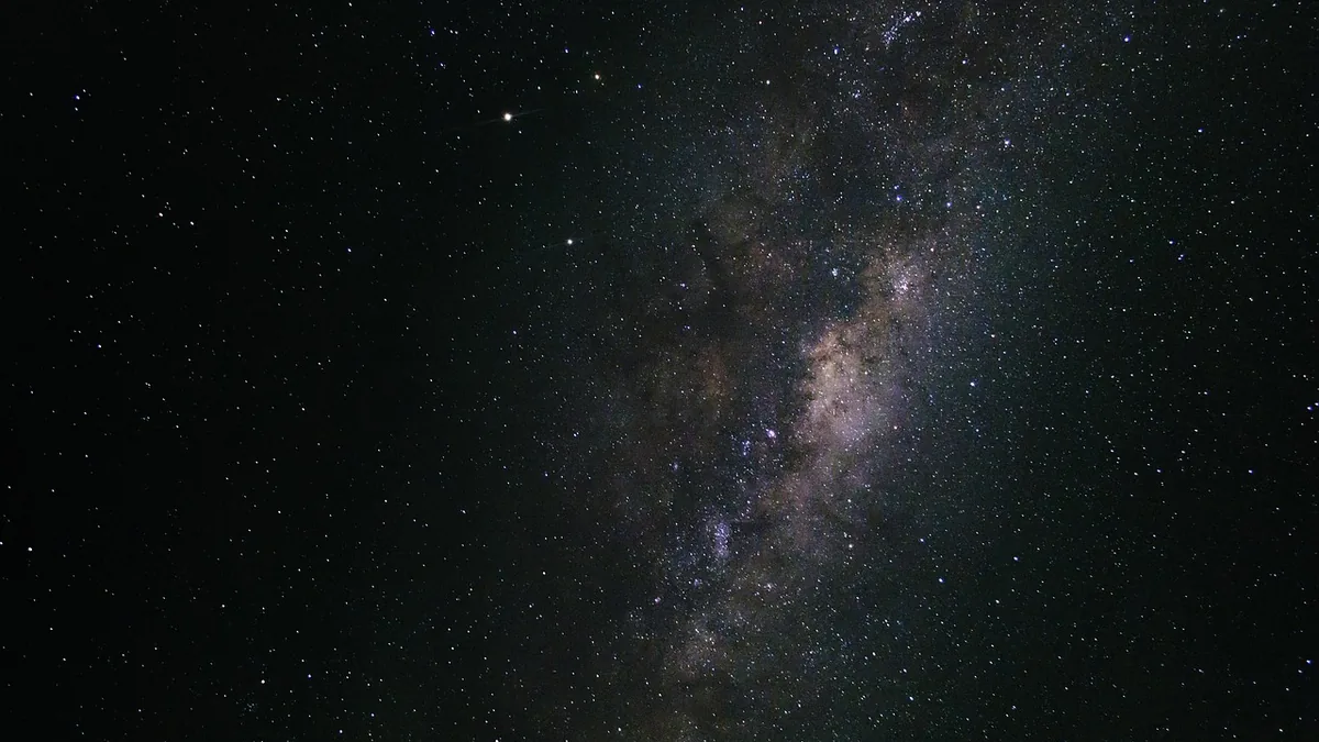 The Milky Way galaxy band stretches diagonally across a dark, star-filled night sky.