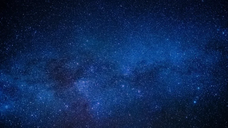A vibrant blue starfield filled with countless stars and cosmic dust, representing deep space.