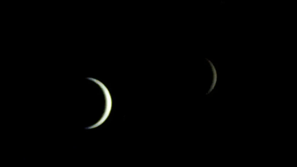 Two crescent celestial bodies glowing softly in the dark expanse of space.