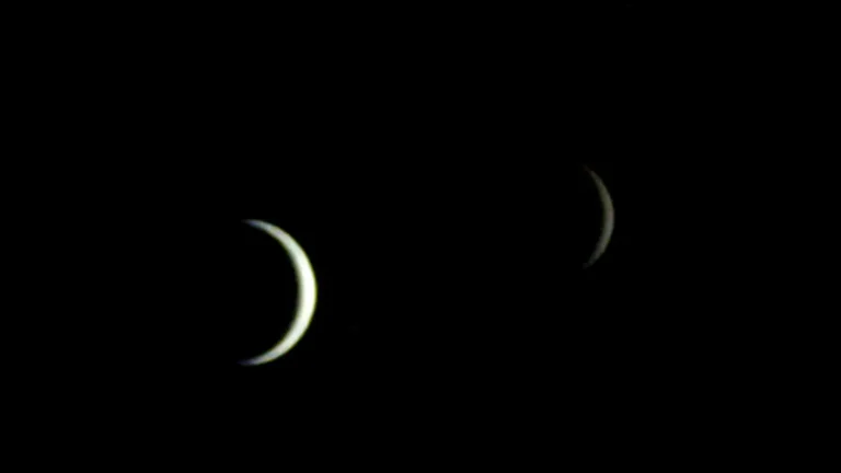 Two crescent celestial bodies glowing softly in the dark expanse of space.