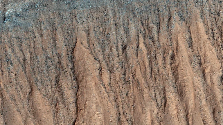 High-resolution view of Martian gullies on a steep slope, showing bluish carbon dioxide frost near the top.