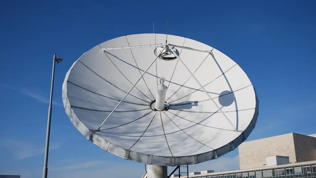 A large white satellite dish antenna against a clear blue sky.