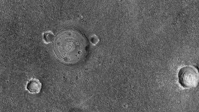 Black and white satellite view of the Martian surface featuring impact craters and polygonal terrain patterns.