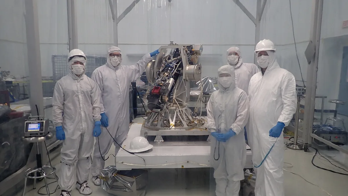 Team in cleanroom suits stands around space hardware for the lunar AI computing experiment.