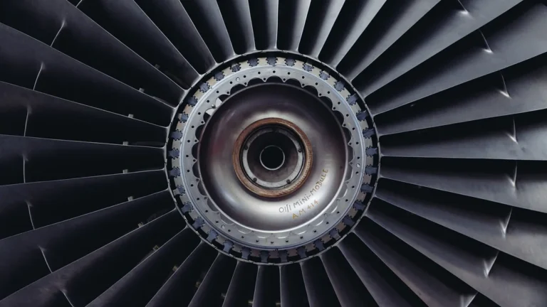 A close-up, symmetrical view of a dark metallic jet engine turbine with a silver central hub.