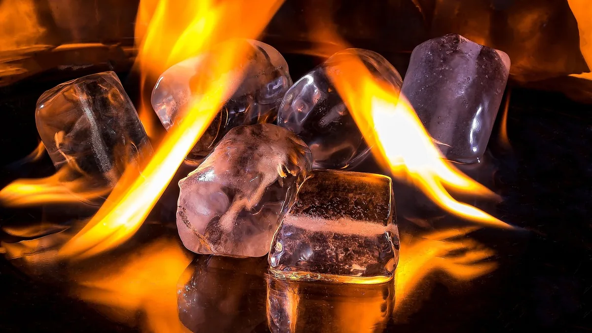 Ice cubes surrounded by vibrant orange flames, symbolizing extreme temperature differences.