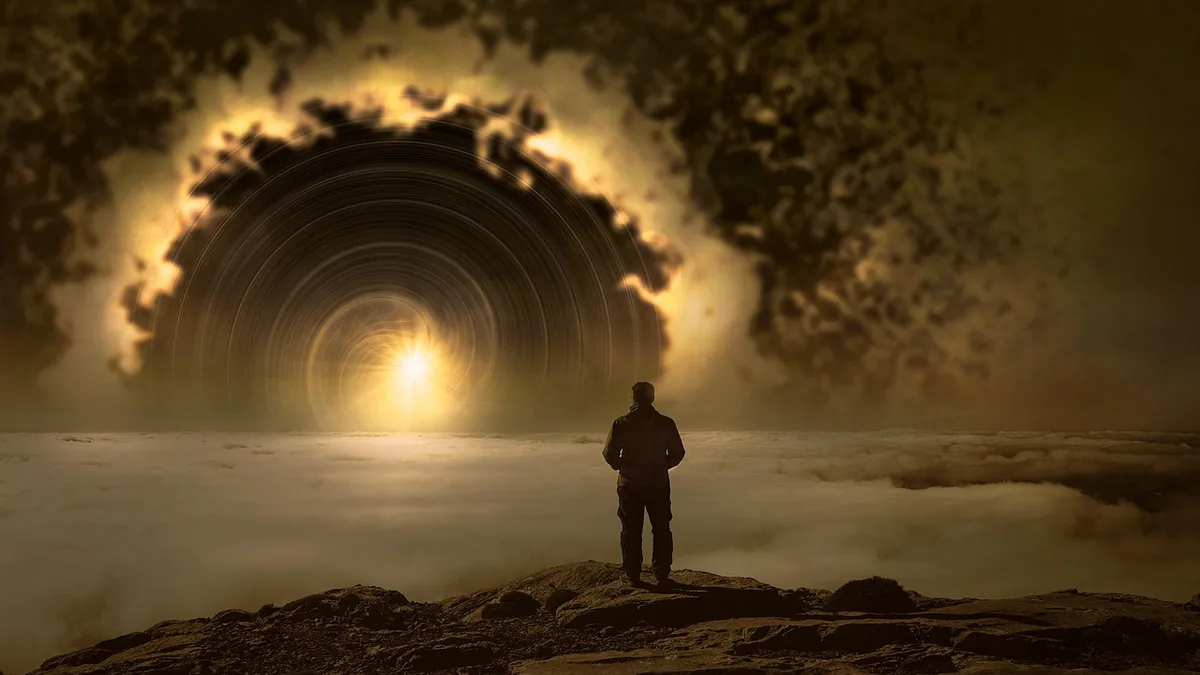 Silhouetted observer stands on a cliff looking at a giant glowing cosmic portal over clouds.