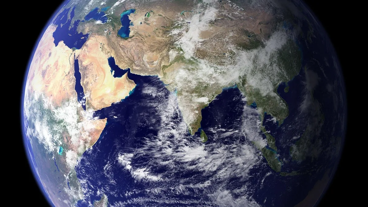View of Earth from space showing the Indian Ocean, India, Asia, and Africa under cloudy skies.