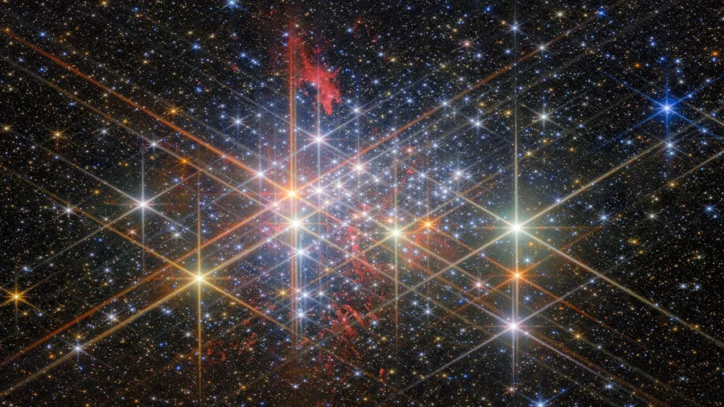 A brilliant star cluster with colorful nebulae and giant crisscrossing diffraction spikes from bright stars.