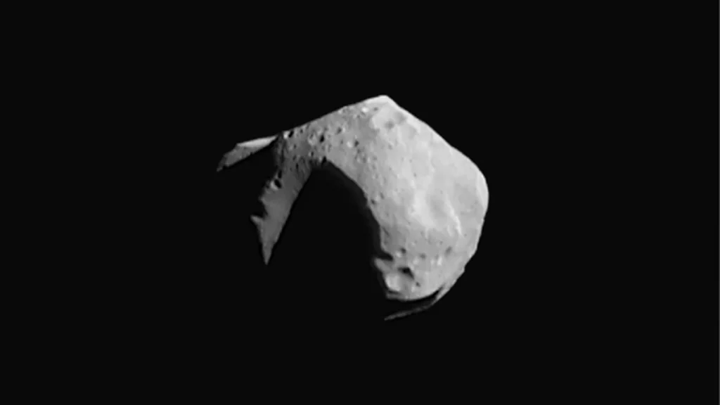 A cratered, irregular grey asteroid against a black space background, representing a Jupiter Trojan asteroid.