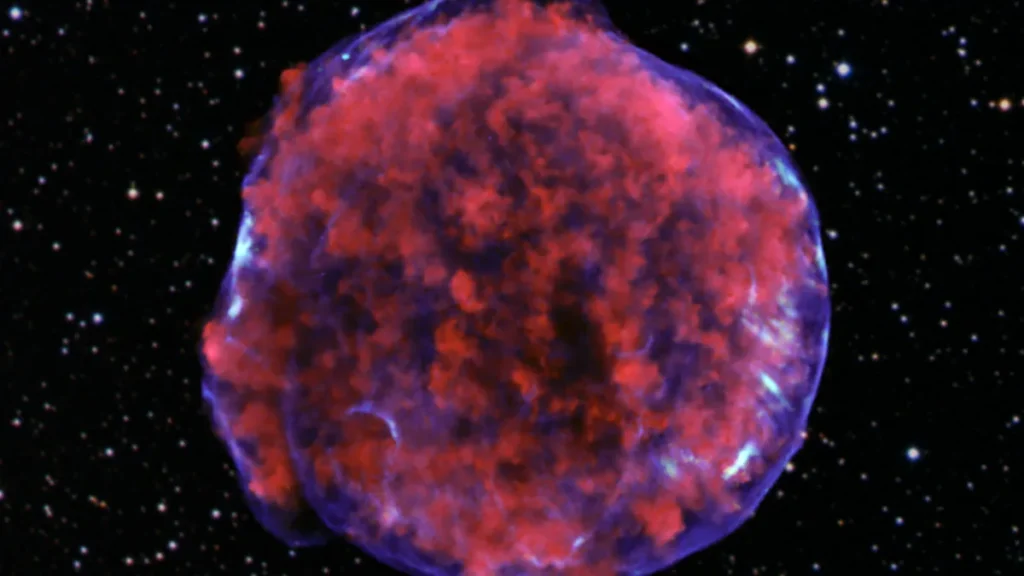 A colorful red and purple supernova remnant resembling a cosmic bubble against a starry black background.