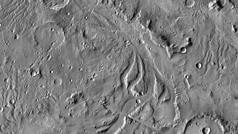 Black-and-white orbital view of Martian craters and winding canyon-like valleys.