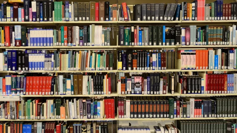 Rows of colorful academic books organized on library shelves, representing scientific literature.