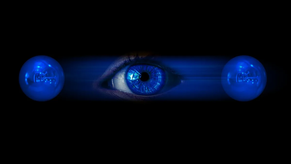 A glowing blue eye with a digital iris, flanked by two blue light bulbs against a black background.