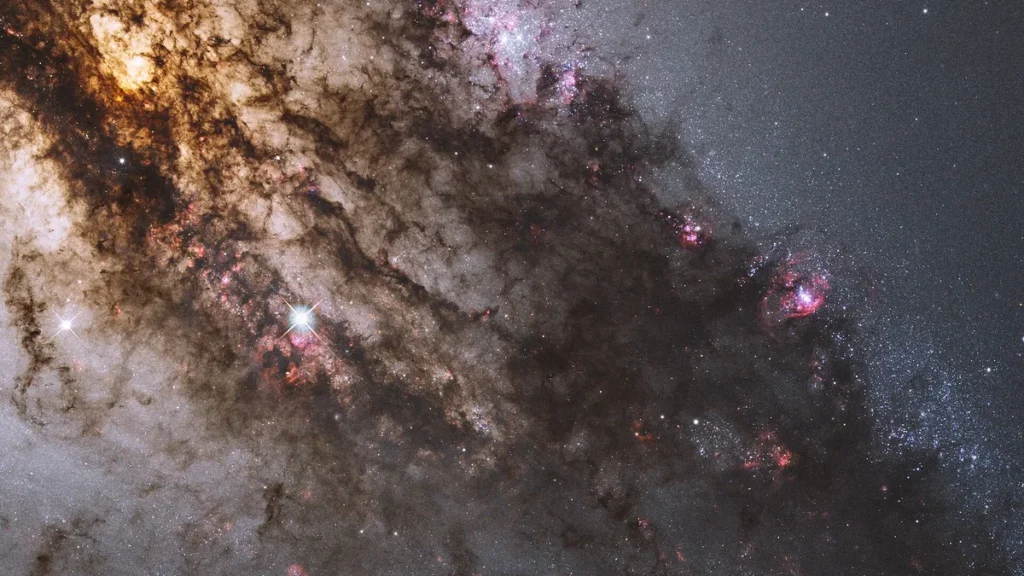 Stunning close-up of a galaxy showing thick dark dust lanes, bright stars, and pink star-forming regions.