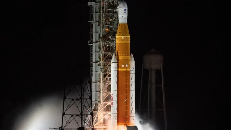 NASA's Artemis rocket stands on the launch pad at night, illuminated by bright floodlights.