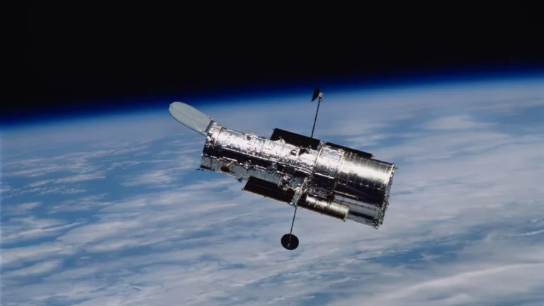 The Hubble Space Telescope floating in orbit with Earth and the dark void of space in the background.