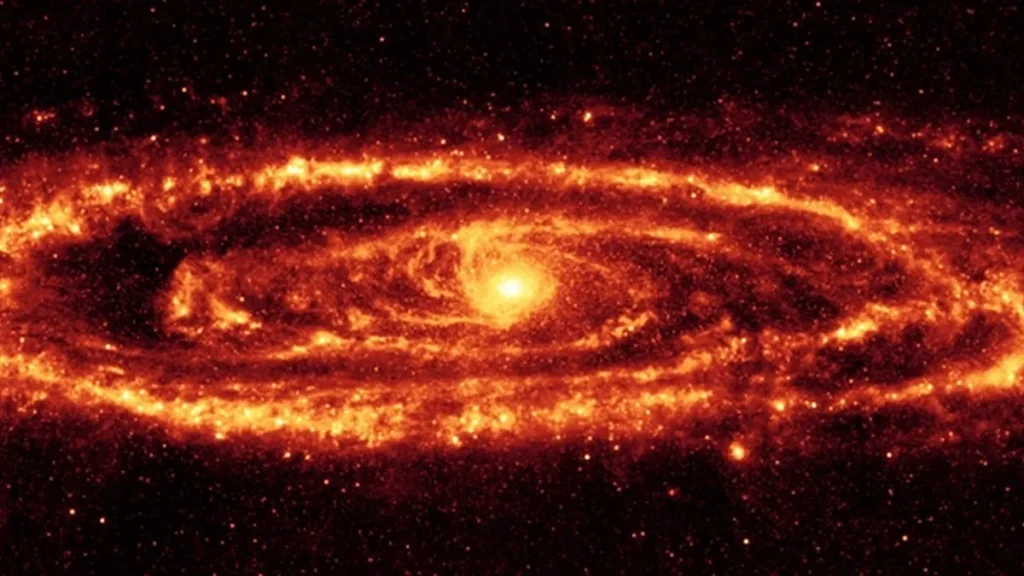 Vibrant orange-red spiral galaxy glowing brightly in infrared against a dark, star-filled cosmic background.