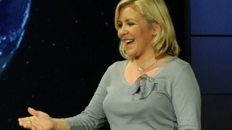 Smiling blonde woman in a grey top presenting with a space-themed background.