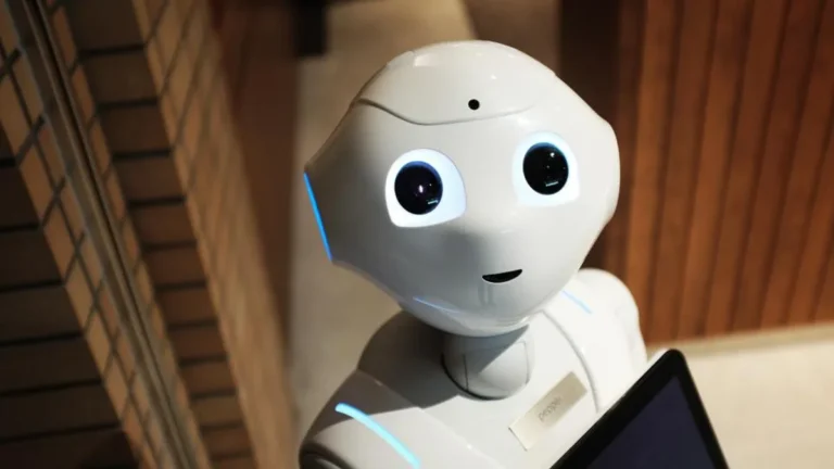 Close-up of a white humanoid Pepper robot with glowing blue eyes, representing advanced robotics technology.