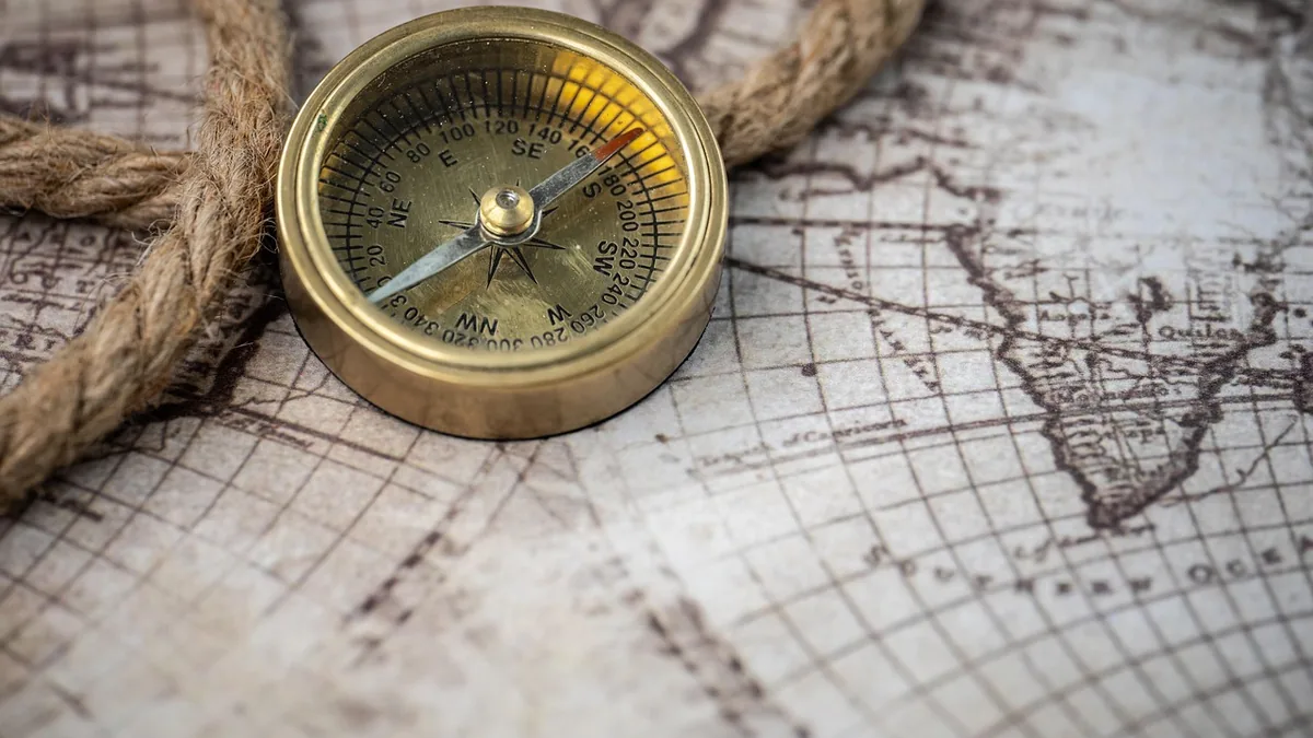 A brass compass lies on a vintage map, symbolizing exploration, navigation, and mapping the unknown.