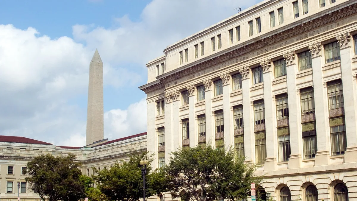 White marble facade of the USDA building with the Washington Monument in the distance.