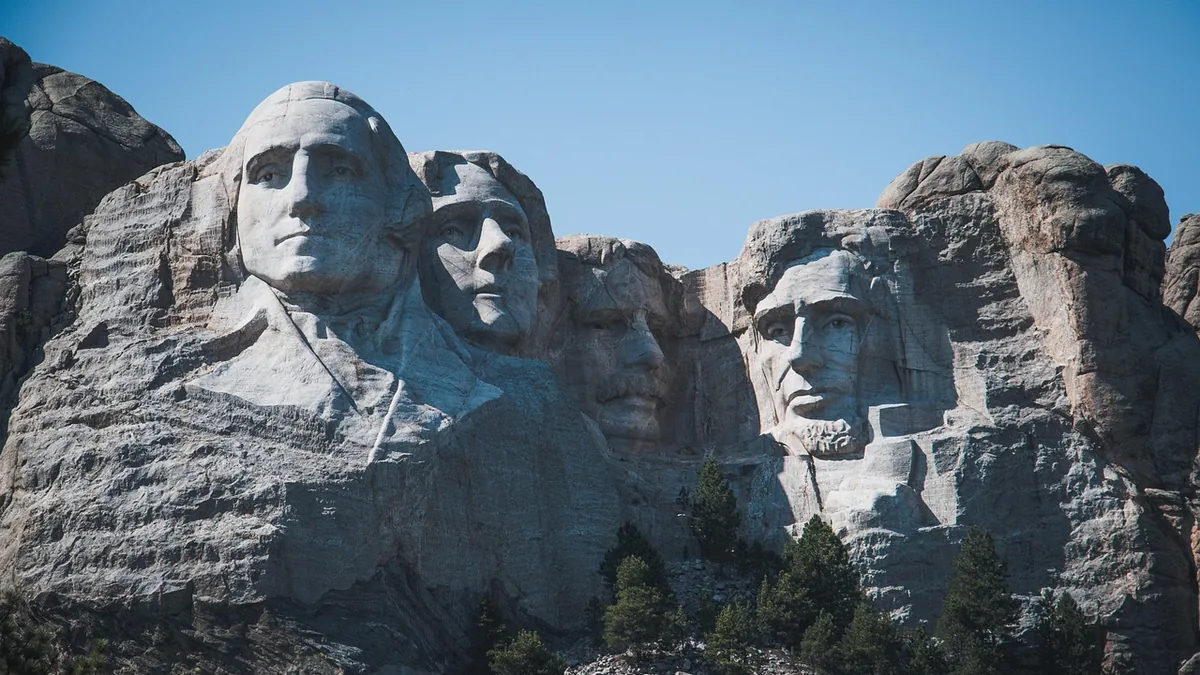 The carved faces of four US presidents on Mount Rushmore under a clear blue sky.