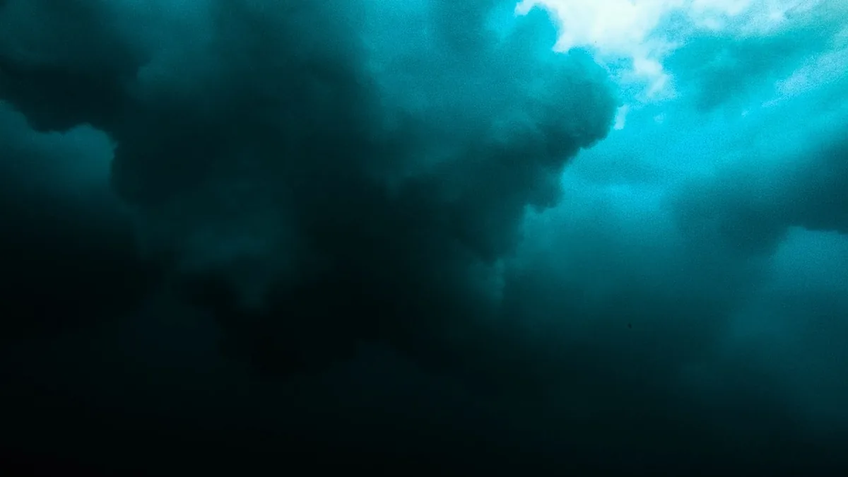 Deep teal underwater clouds with bright light filtering from the top right, evoking a mysterious subsurface ocean.
