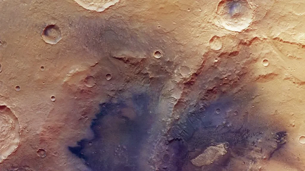 Colorful orbital view of Martian cratered surface showing diverse geological colors.