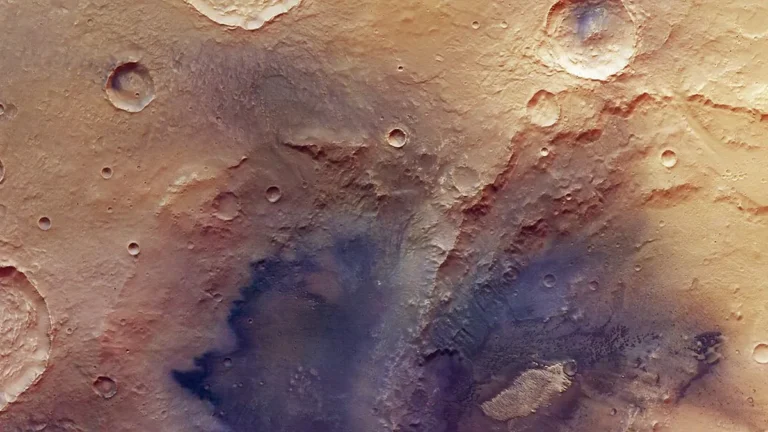Colorful orbital view of Martian cratered surface showing diverse geological colors.