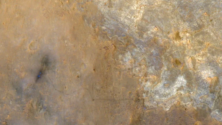 Satellite image of Martian terrain showing the winding tracks of the Perseverance rover, marked by a small blue dot.