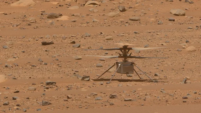 The Ingenuity helicopter stands on the red, rocky, dusty surface of Mars.