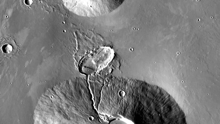 Black-and-white orbital image of Martian craters with a prominent channel and geological formations.