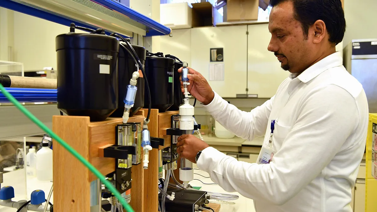 Scientist adjusting lab equipment for water isotope analysis in a clean laboratory setting.