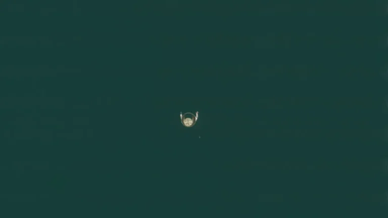 Small satellite deployed in space, centered against a vast dark greenish background.