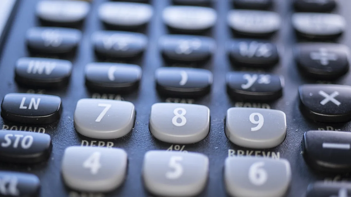 Close-up of a black scientific calculator showing grey numeric keys and mathematical functions, symbolizing calculation.