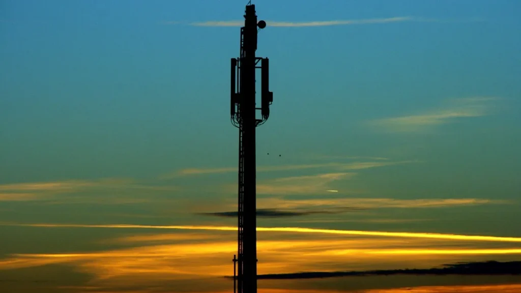 Silhouette of a cell tower against a colorful sunset sky.