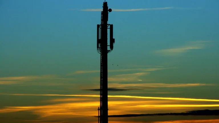 Silhouette of a cell tower against a colorful sunset sky.