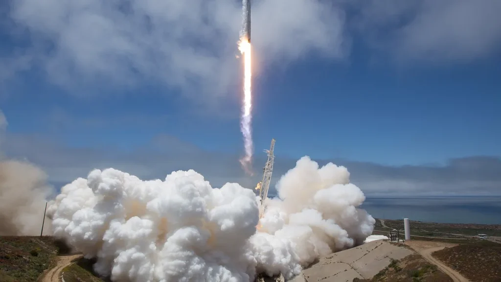 SpaceX rocket launch leaving a massive white smoke cloud under a blue sky at Vandenberg.