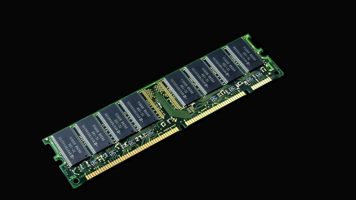 A green computer RAM module with black memory chips on a clean black background.